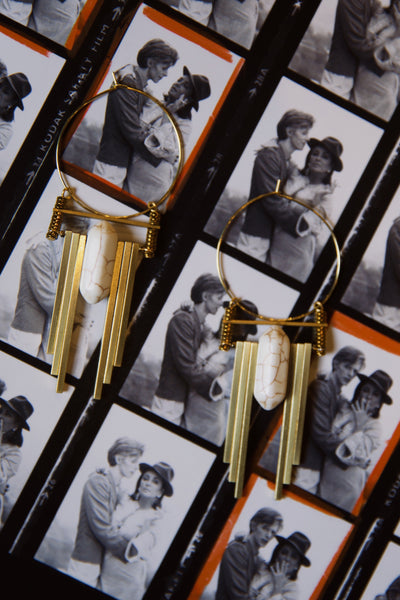 Gold earrings with decorative elements on a background of black and white photos.